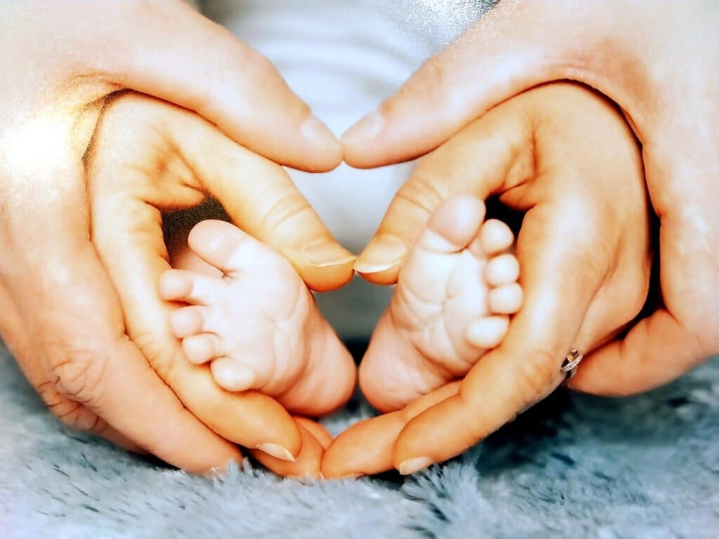 VanessaMatthieuMarcus Les pieds de Marcus entourés par les mains de Vanessa et Matthieu formant un cœur
